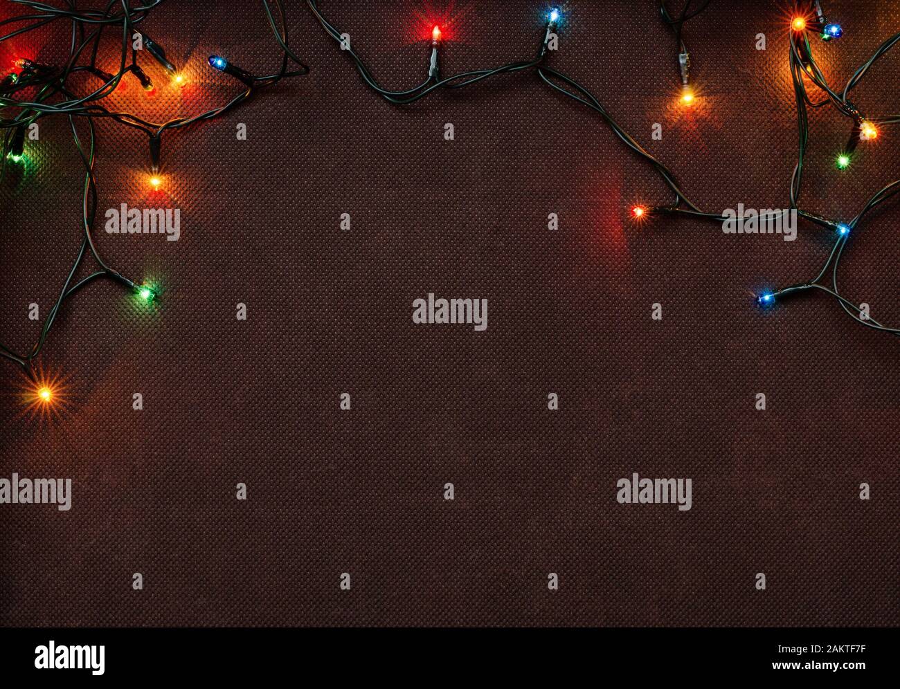 Christmas garland with colorful lights on brown textile background