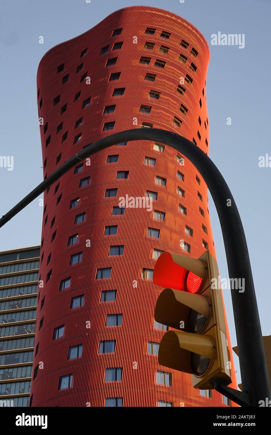 Unusual red skyscraper city building in a conceptual style behind traffic lights Stock Photo