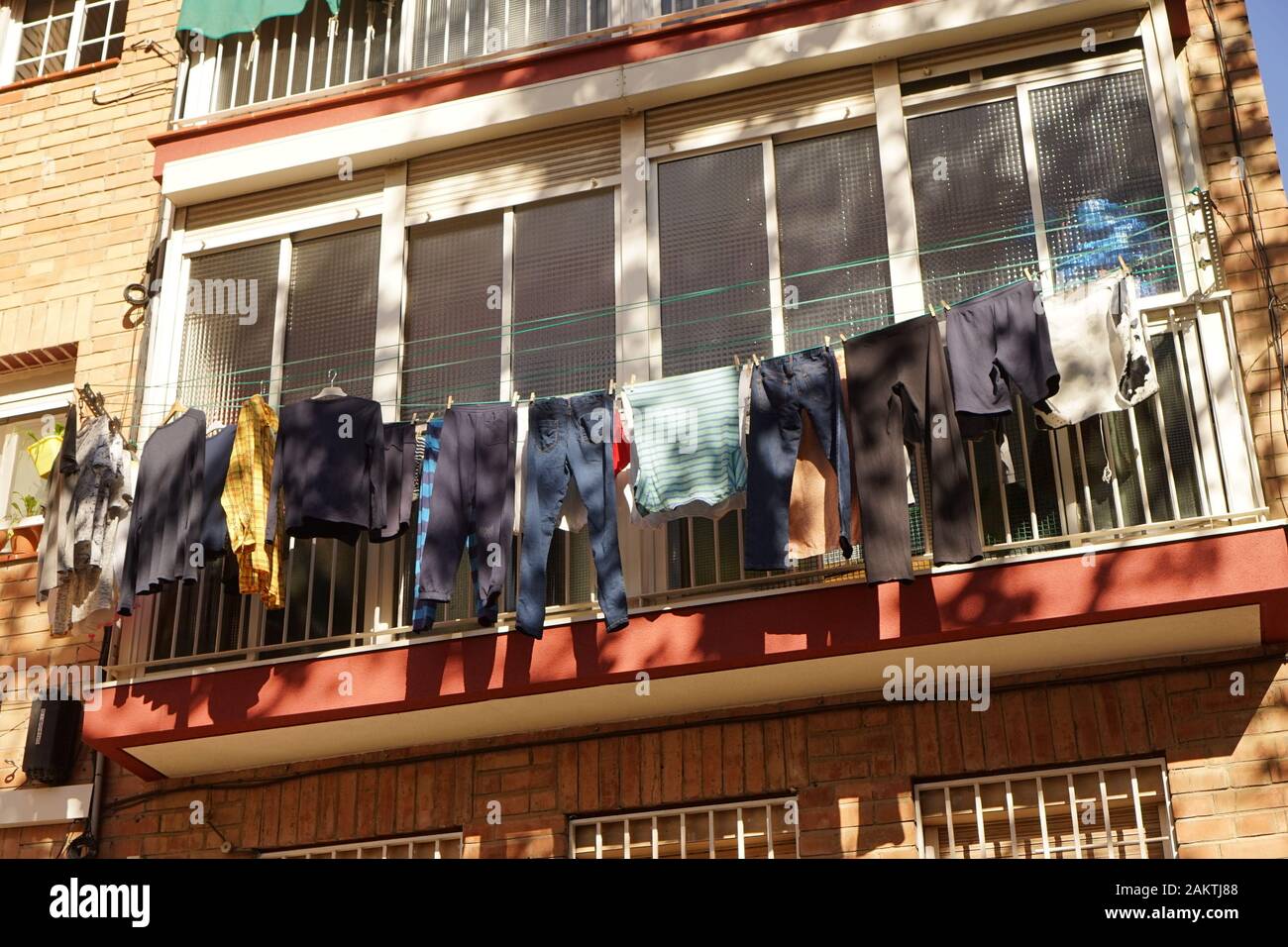 laundry hanging out to dry on an apartment enclosed balcony Stock Photo