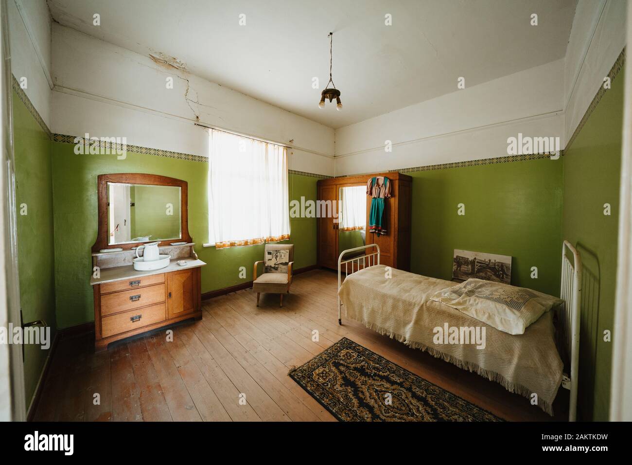 Interior of a colonial green sleeping room with bed and furnitures