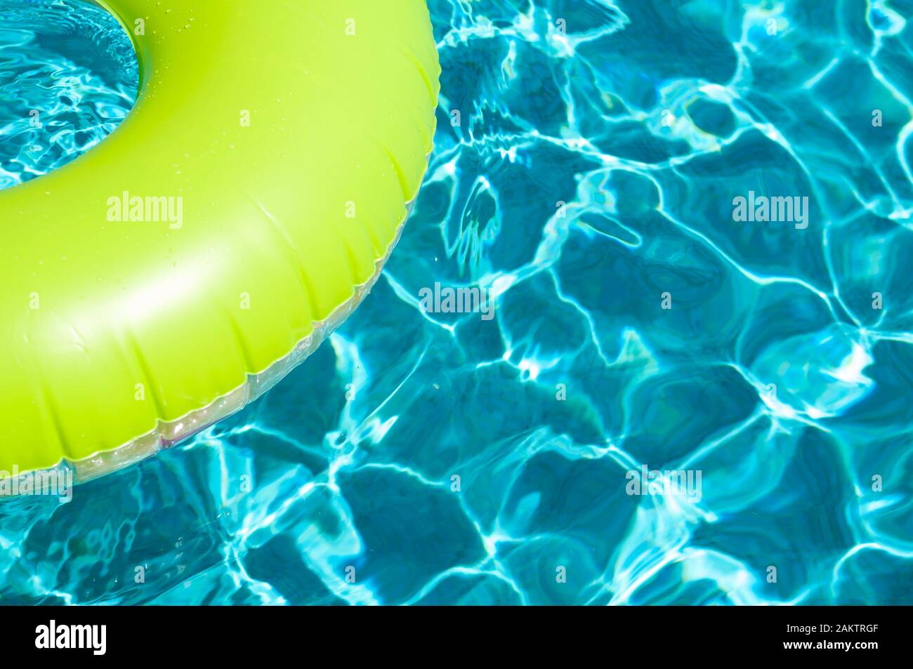 Brightly colored pool ring floating on dappled turquoise water in ...
