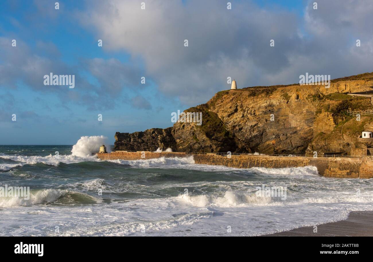 Stormy weather at Portreath, Cornwall, UK with waves breaking over the Monkey Hut and the Pepperpot visible on the high cliff. Stock Photo