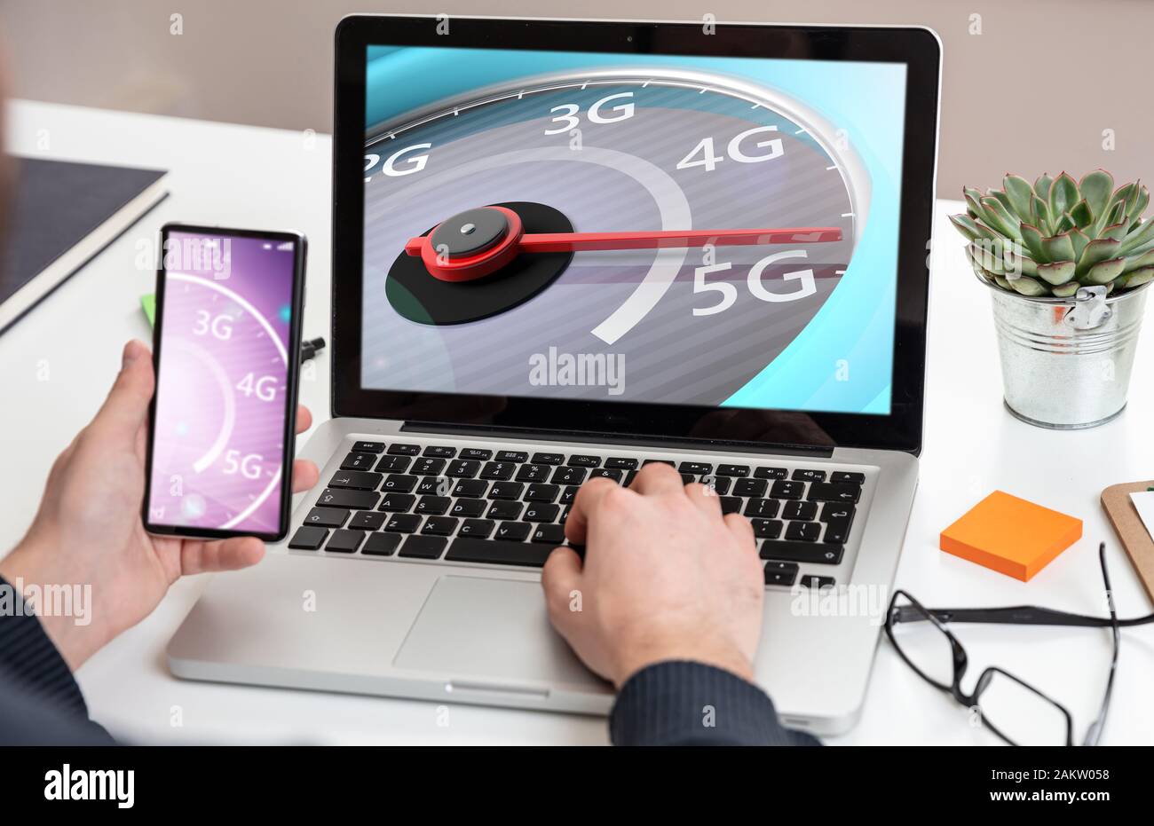 5G, internet speed test, high speed concept. Man holding a mobile phone, speedometer 5G speed network connection on the computer laptop screen, busine Stock Photo