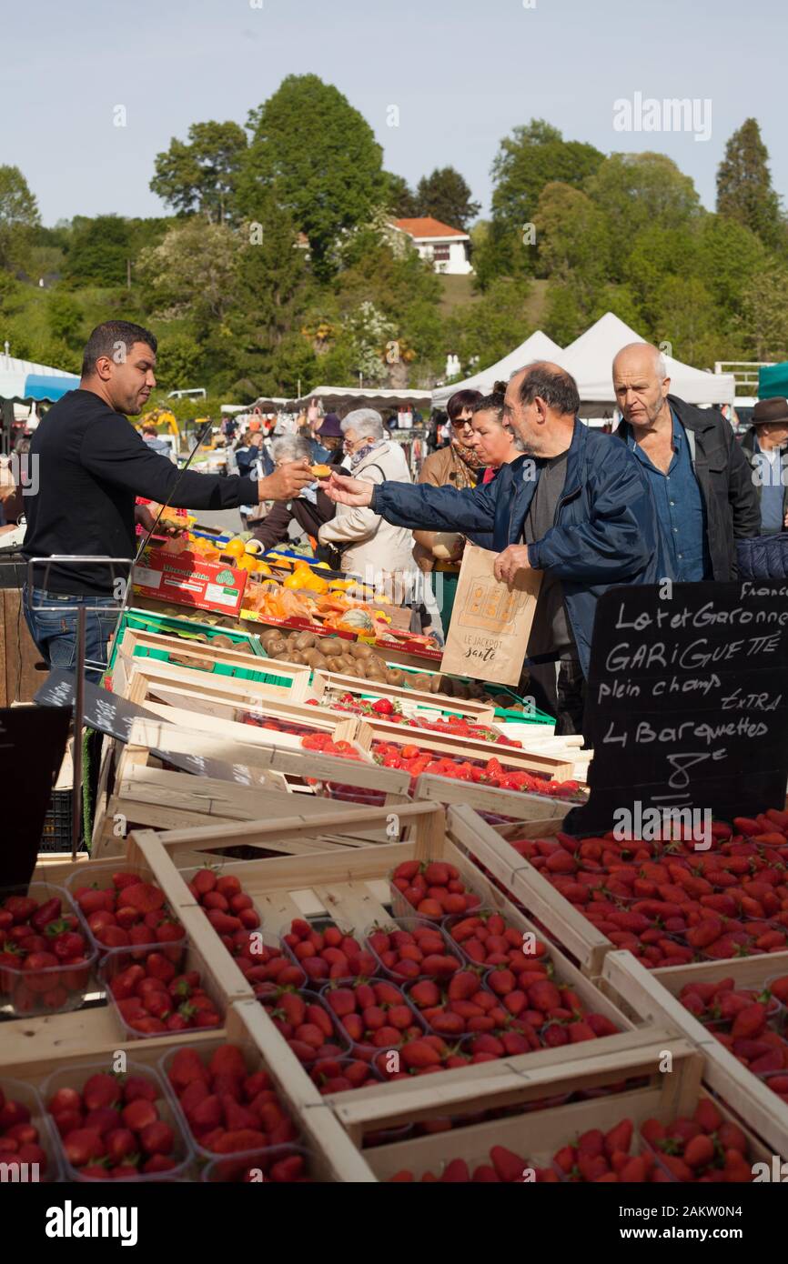 Customer trying a piece of fruit at the market in Nay,Pyrenees Atlantiques, Nouvelle Aquitaine, France Stock Photo