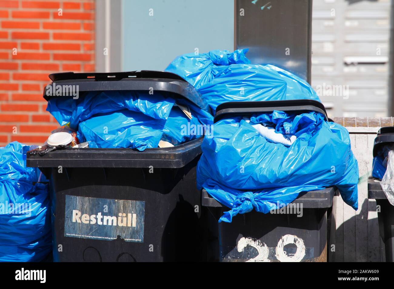 Blue garbage bags and black garbage bins for residual waste standing on