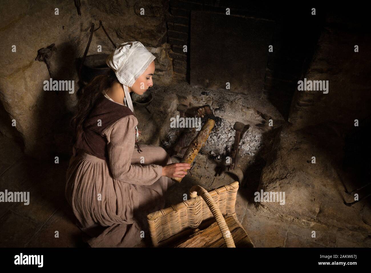 Renaissance portrait in Rembrandt style of a young woman in medieval peasant costume working near the authentic fireplace of a property released Frenc Stock Photo