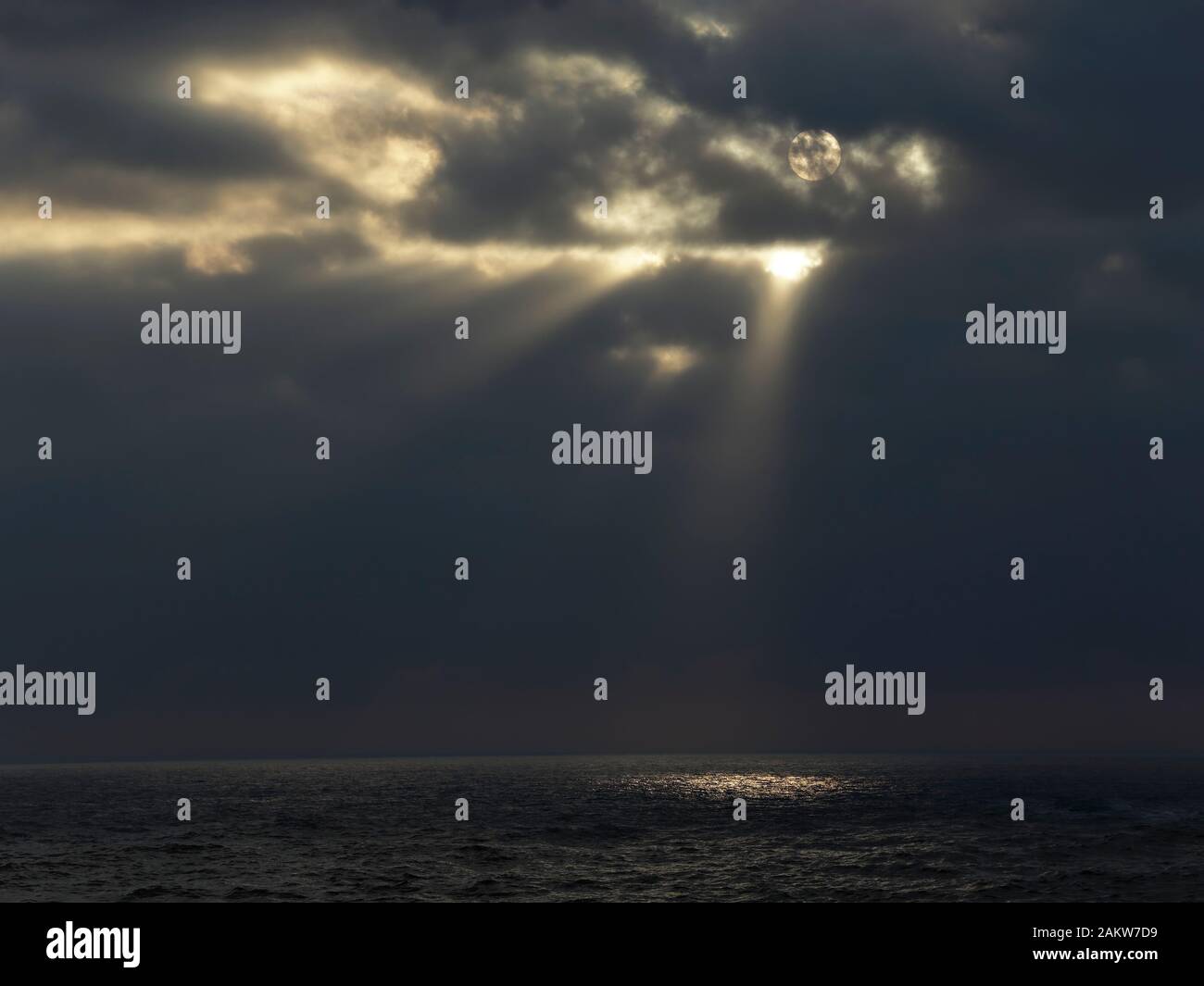 Cloudy full moon night with light beams at sea Stock Photo Alamy