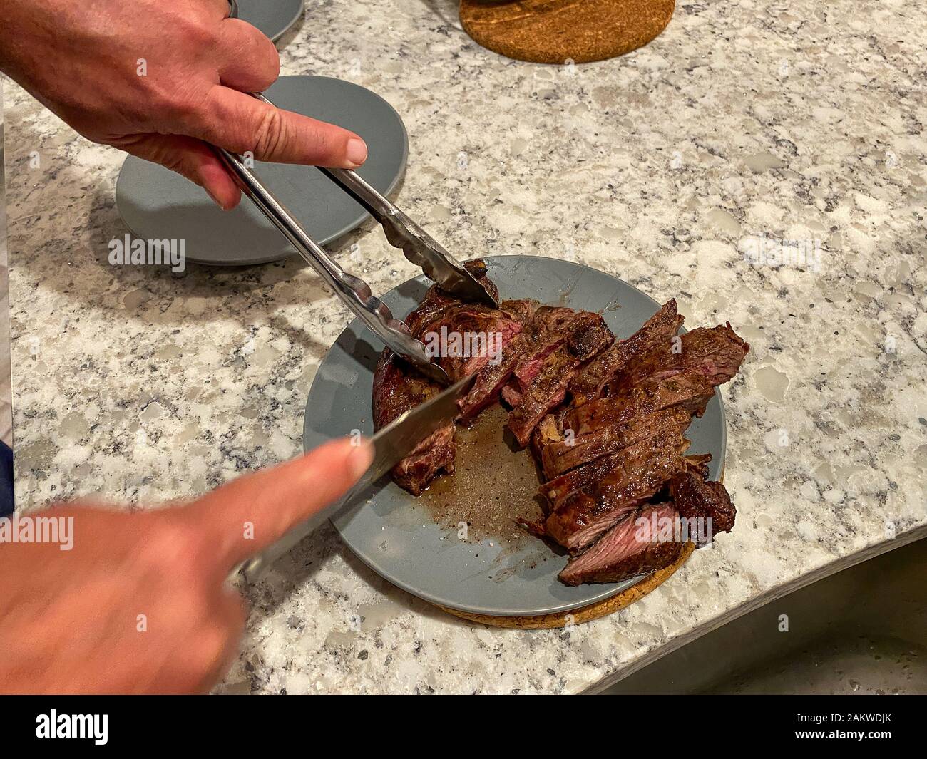 https://c8.alamy.com/comp/2AKWDJK/a-man-cutting-a-ribeye-steak-on-a-blue-plate-in-preparing-to-serve-it-for-dinner-2AKWDJK.jpg