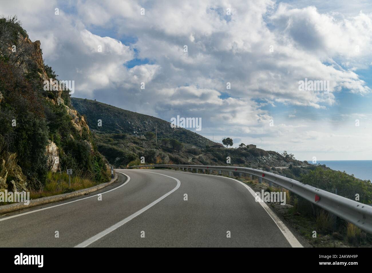 A sharp bend on an empty tarmac road with street signs. Edge of the cliff Stock Photo
