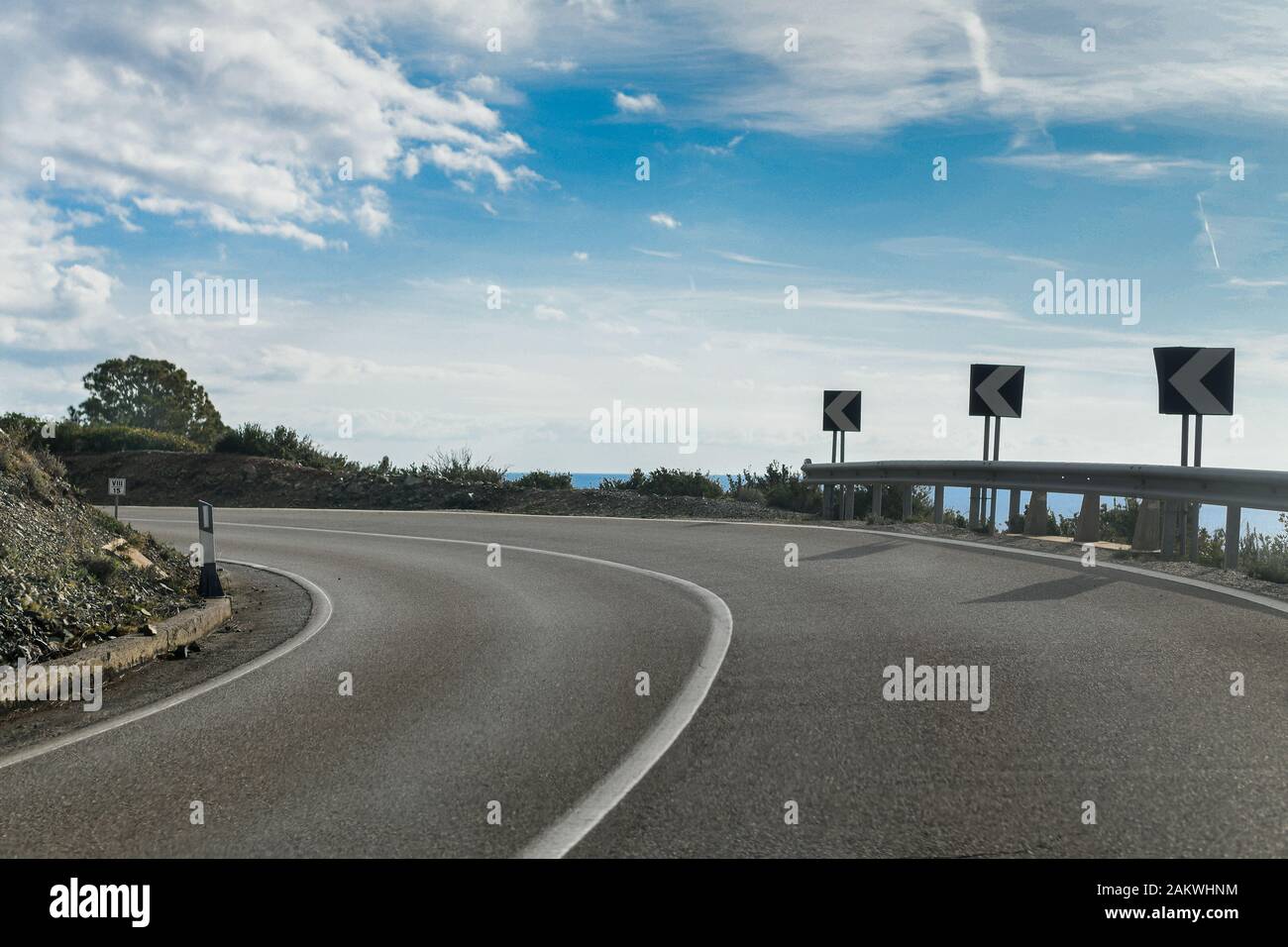 A sharp bend on an empty tarmac road with street signs. Edge of the cliff Stock Photo