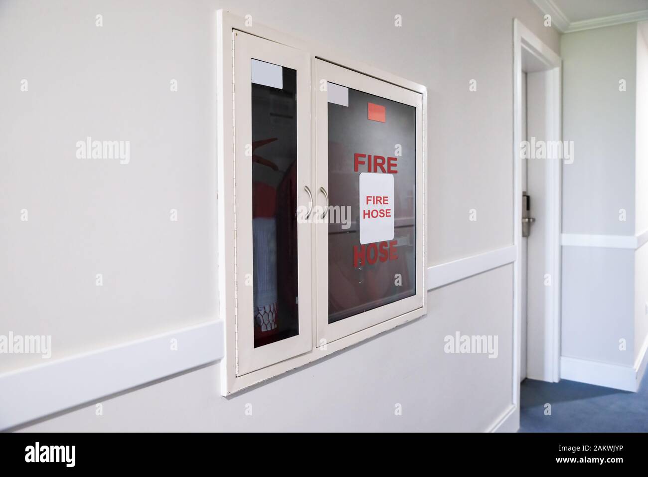 Fire Hose Reel And Fire Extinguisher In Hotel Corridor Stock Photo