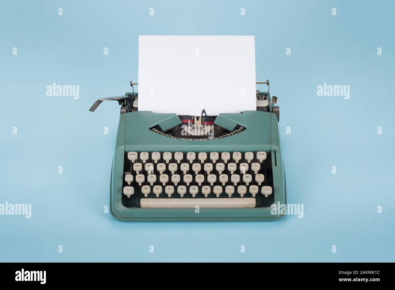 Retro old typewriter with paper on light blue background Stock Photo