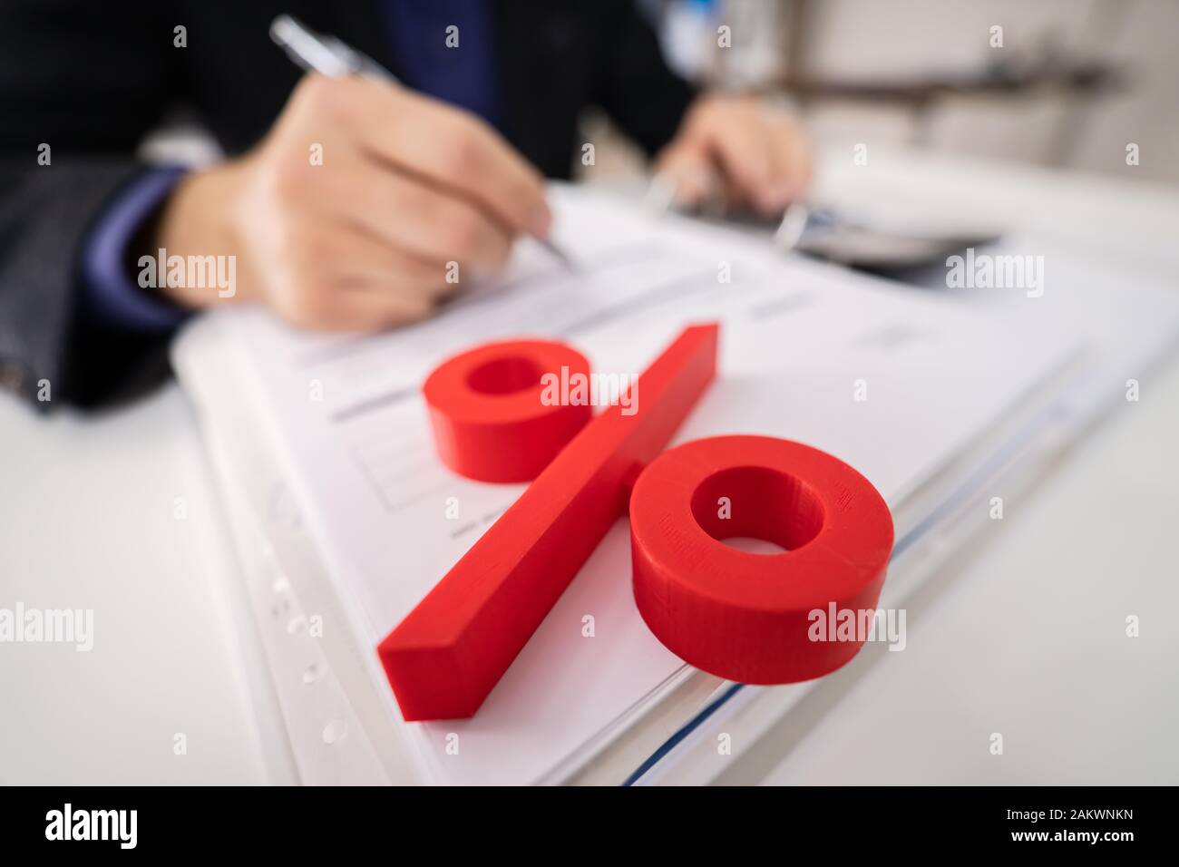 Close-up Of Percentage Symbol In Front Of Businessperson Calculating Invoice Stock Photo