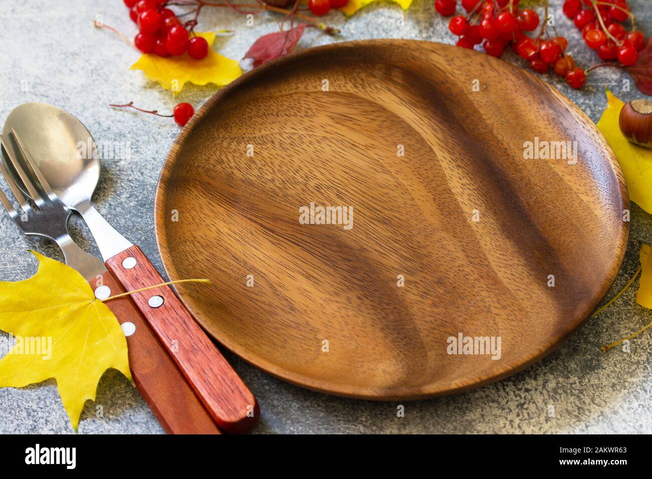 Autumn table setting. Thanksgiving or autumn harvest table setting with silverware and frame of leaves. Free space for your text. Stock Photo