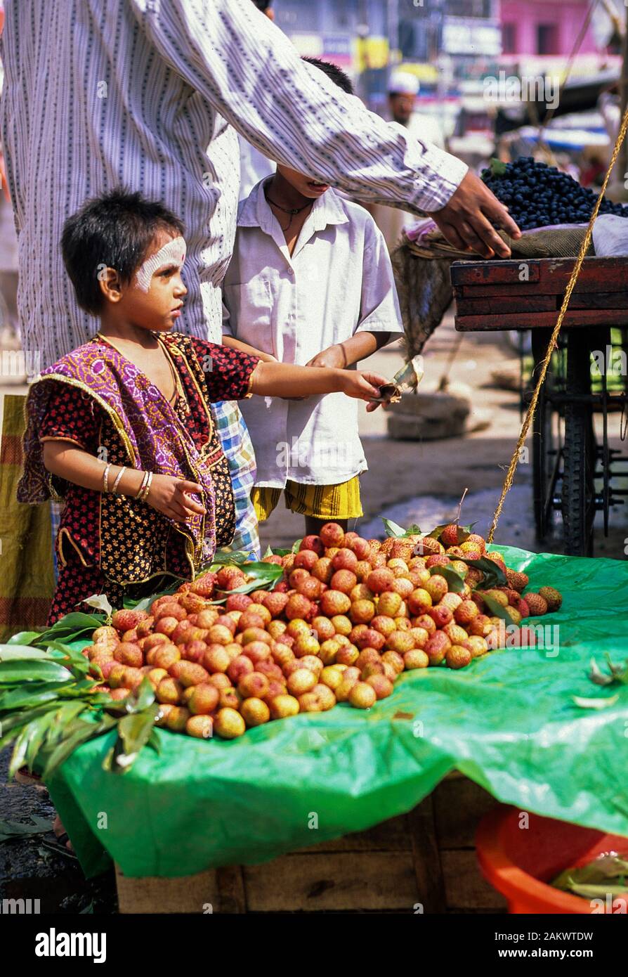 Young Indian child buying Rambutan's in Varanasi, India Stock Photo