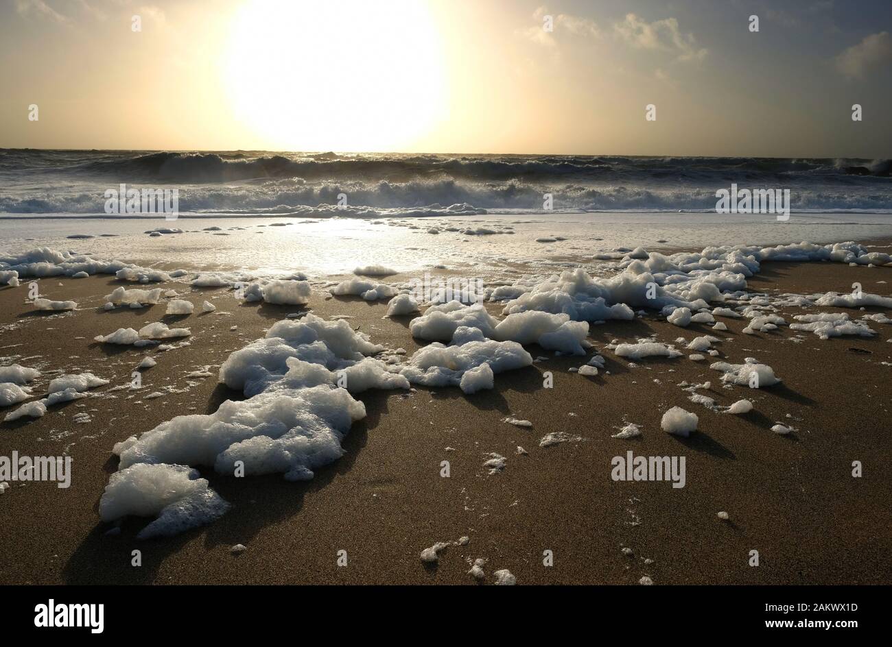 Spume, also known as sea foam, ocean foam or beach foam at Gunwalloe beach, Cornwall, UK - John Gollop Stock Photo