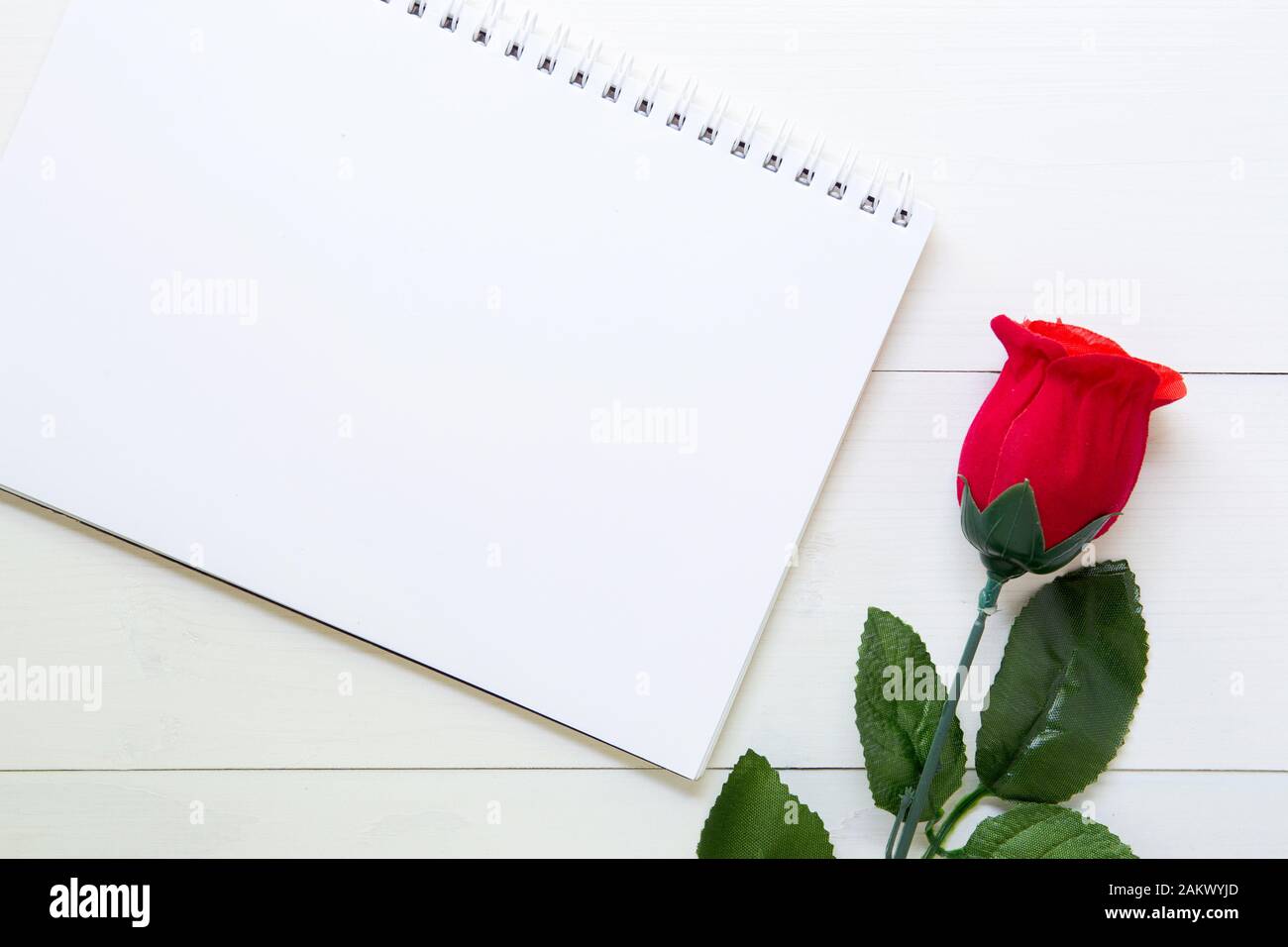 Present gift with red rose flower and notebook on wooden table, 14 February of love day with romantic, copy space with note or diary writing text for Stock Photo