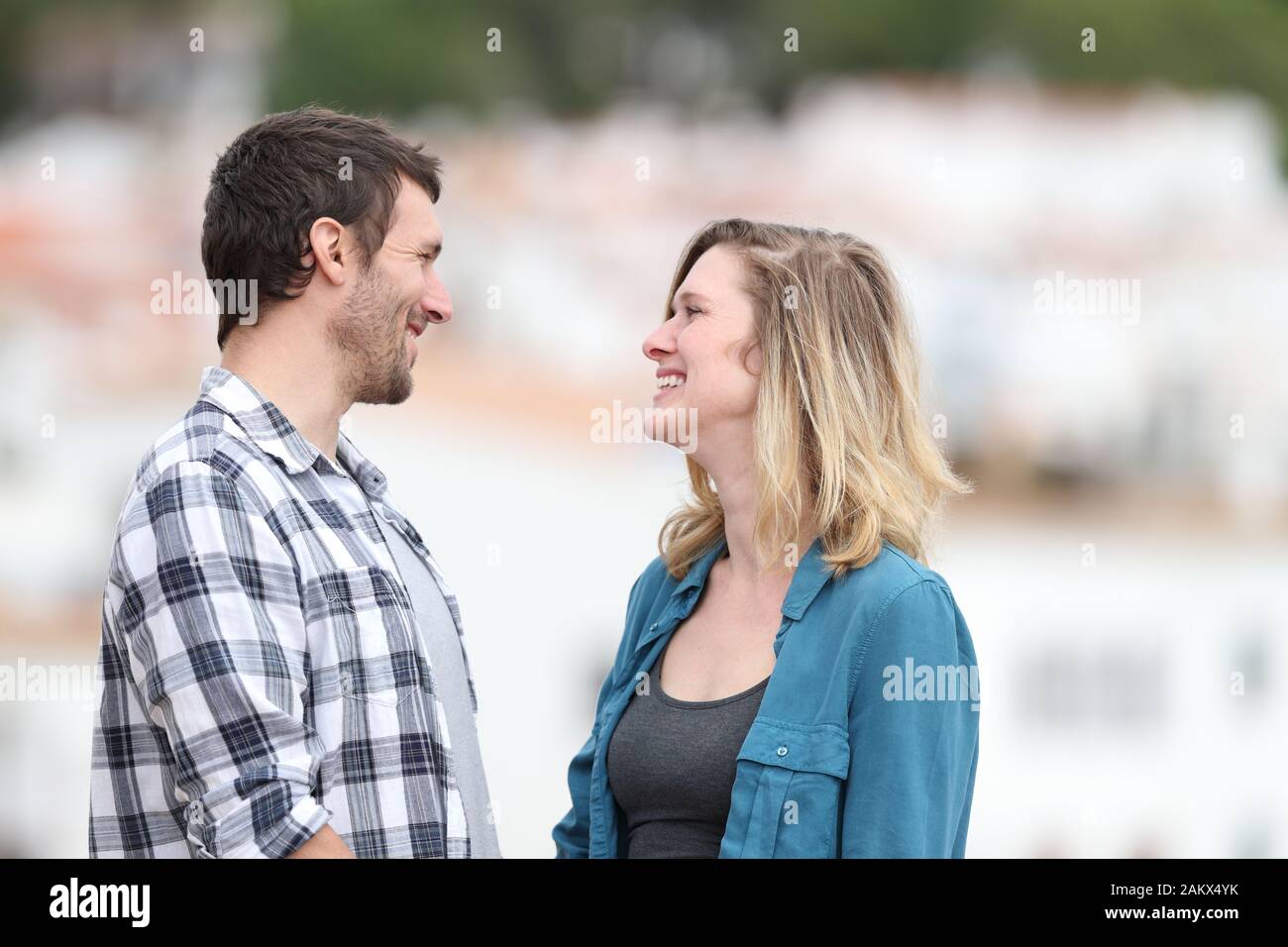 Side view portrait of a man and woman looking each other falling in love in a town Stock Photo