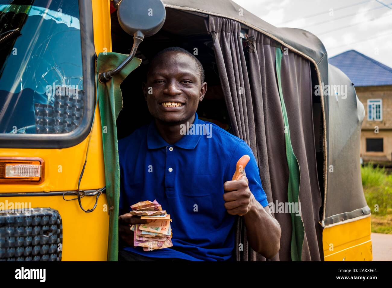 young african man driving a rickshaw taxi counting his money smiling giving a thumbs up Stock Photo