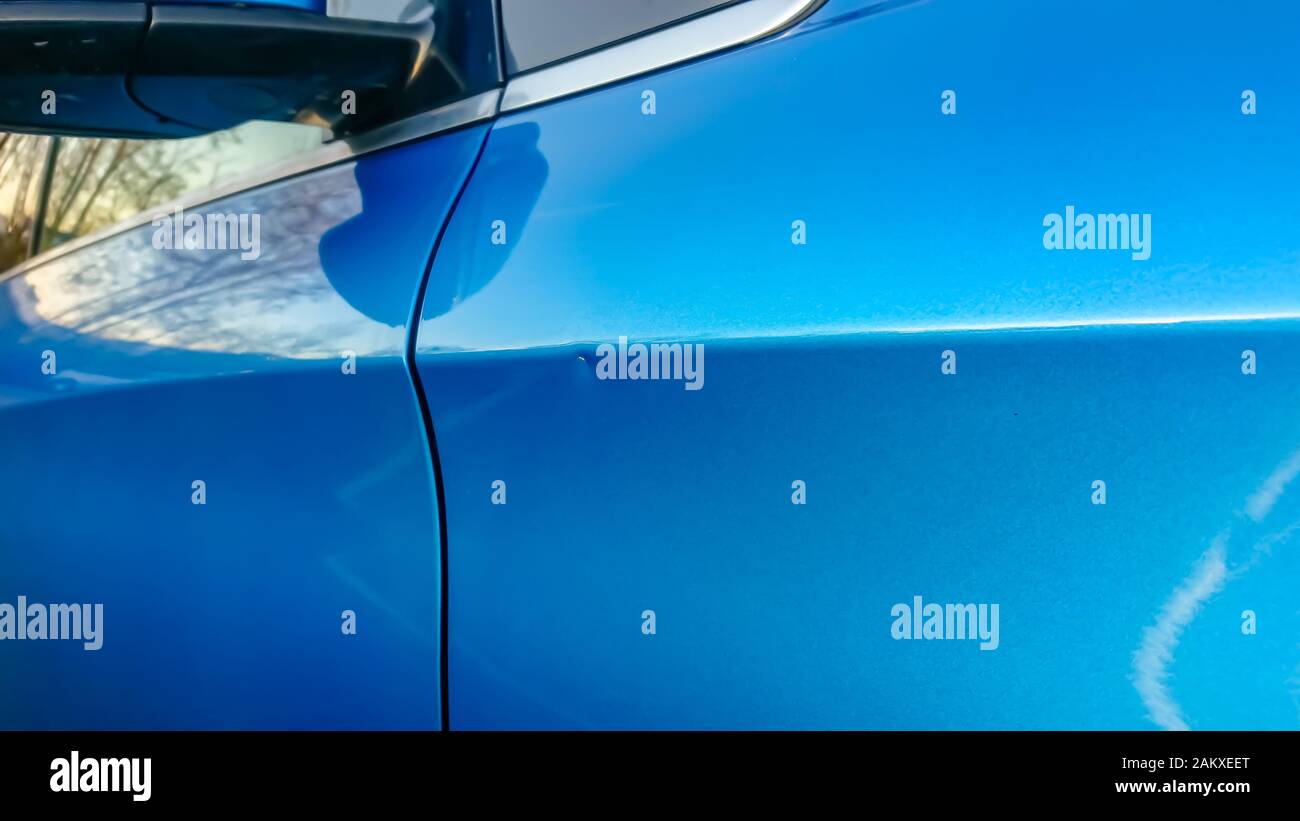 A small dent in the fender of a blue metallic European car Stock Photo
