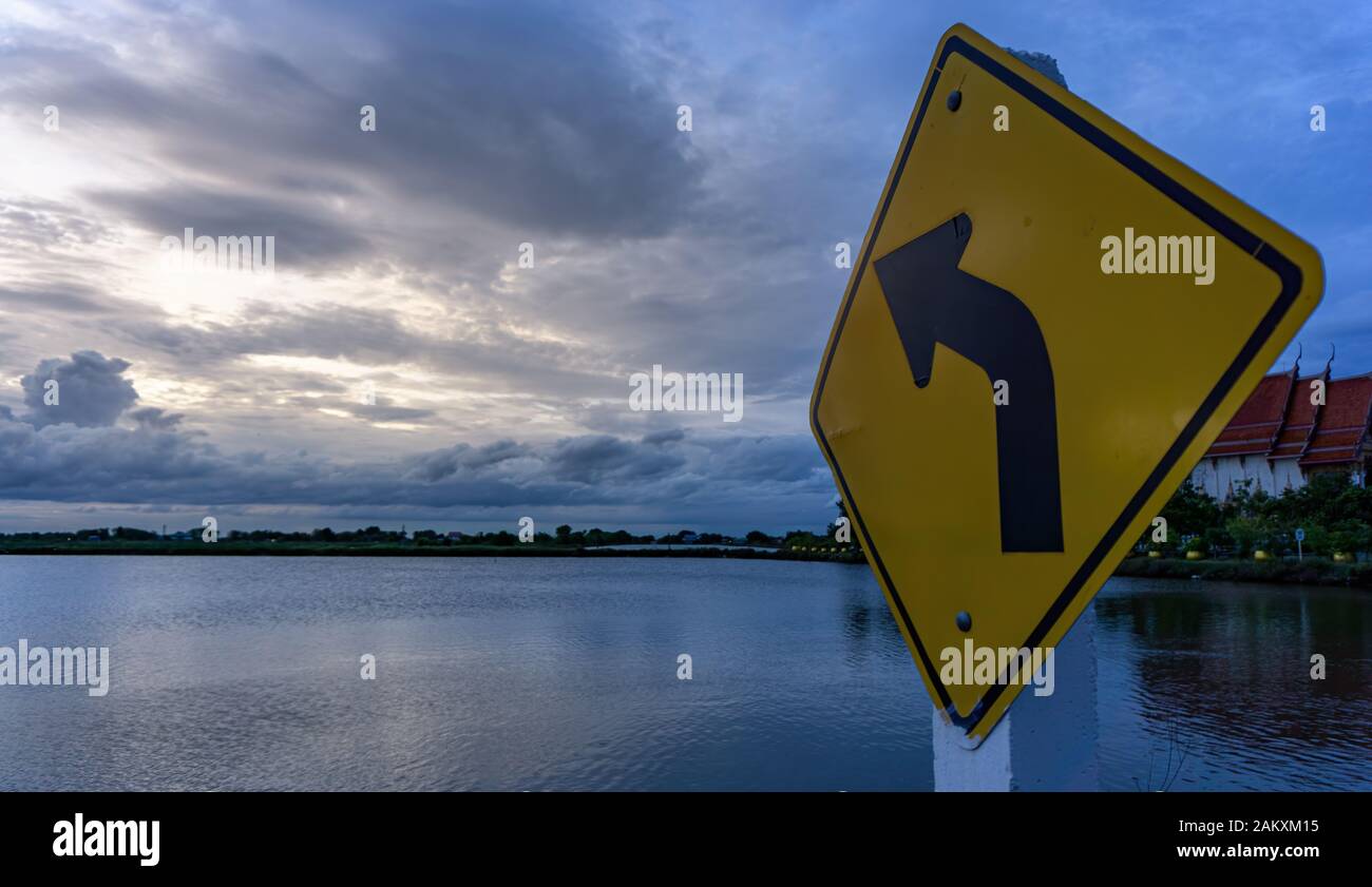 The signs on the left curve point towards the clouds. The sky after the sunset Stock Photo