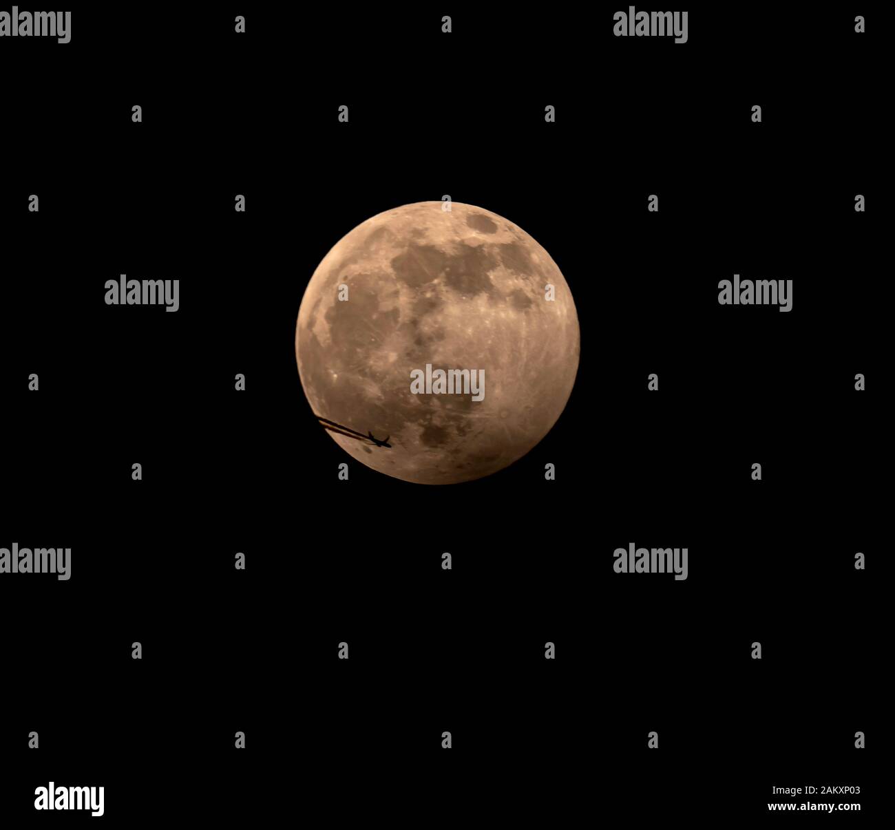 London Uk 10th January 2020 The Full Wolf Moon Displaying A Penumbral Lunar Eclipse With The Disc Of The Moon Passing Earths Shadow A Passing High Flying Airliner Cuts Across The Disc