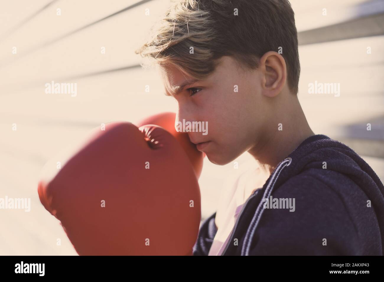 Portrait of handsome young male with boxing gloves ahead the face. Boy ready for a boxe workout defending the head with hands. Boxer ready to throw Stock Photo