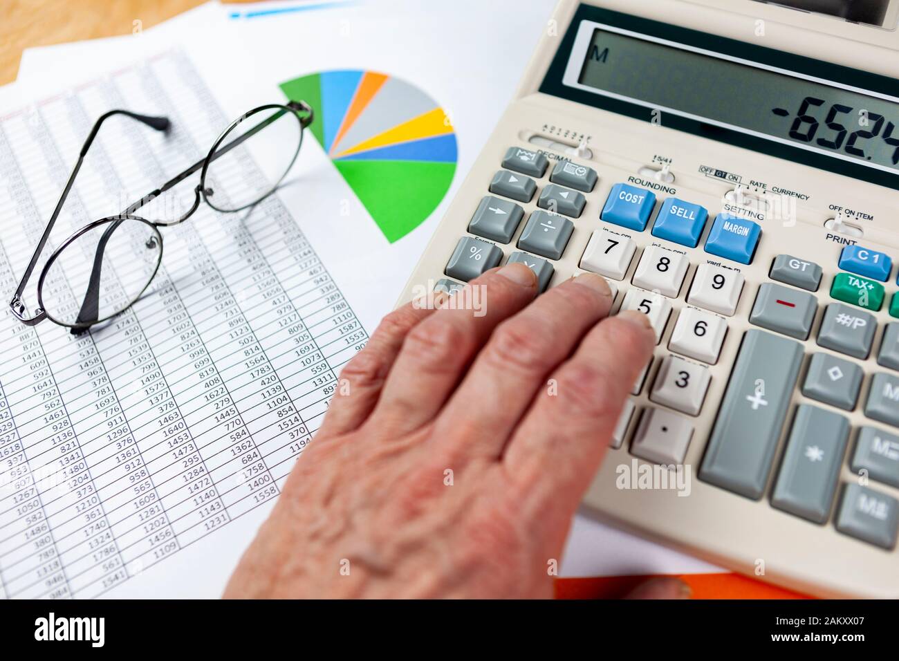 Accountant At His Desk Checking A Spread Sheet Printout With A