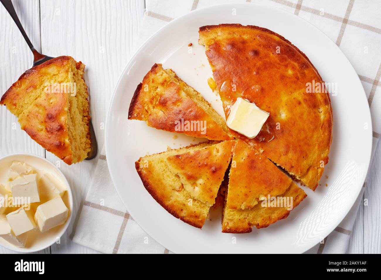 Homemade sliced Buttermilk Cornbread topped with melted butter served on a plate, flatlay, close-up Stock Photo