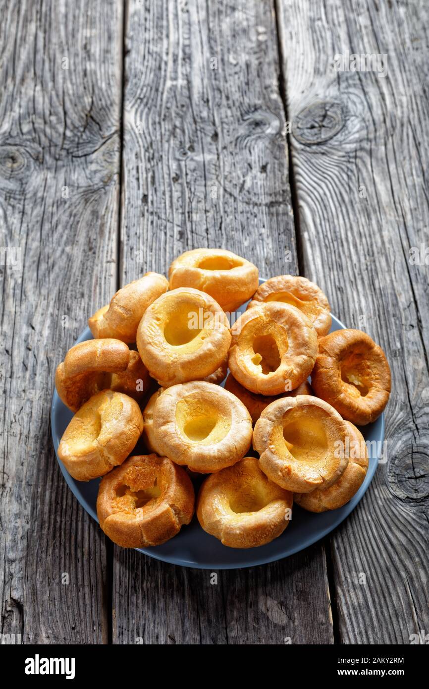 close-up of classic Yorkshire puddings on a plate on a wooden table, english cuisine, vertical view from above Stock Photo