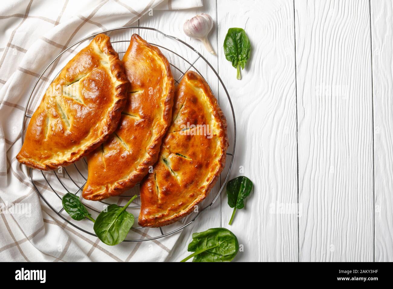 three freshly baked calzones with Spinach and Cheese filling cooling on ...