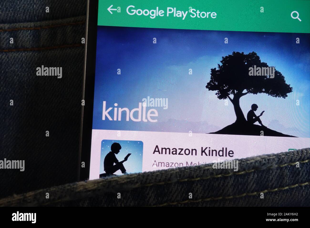 Kindle app on Google Play Store website displayed on smartphone hidden in jeans pocket Stock Photo
