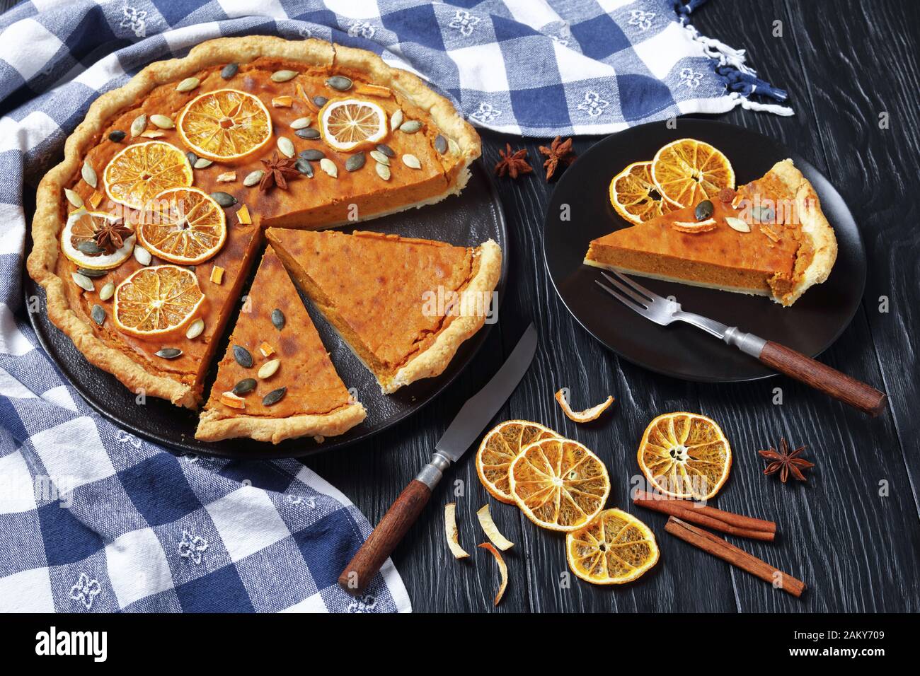 sliced Sweet potato pie decorated with orange chips, pumpkin seeds and anise stars on a black wooden table, horizontal view from above Stock Photo