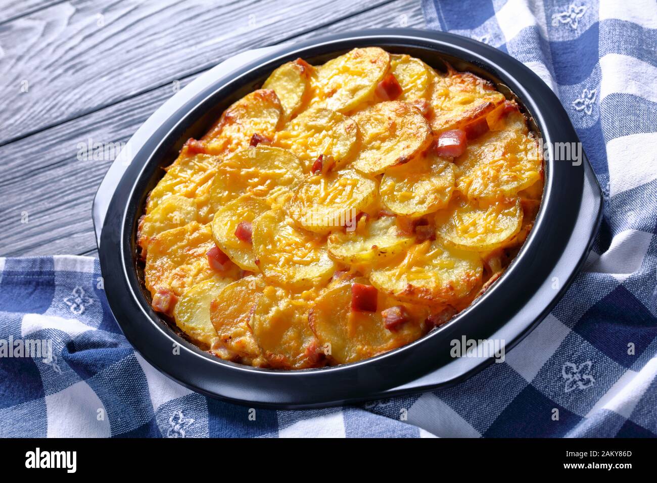 Old fashioned scalloped potatoes and ham with melted cheese in a baking dish, close-up Stock Photo