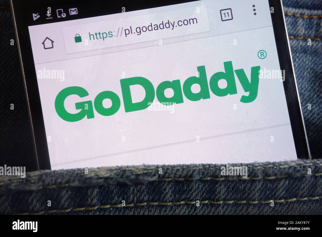 GoDaddy website displayed on smartphone hidden in jeans pocket Stock