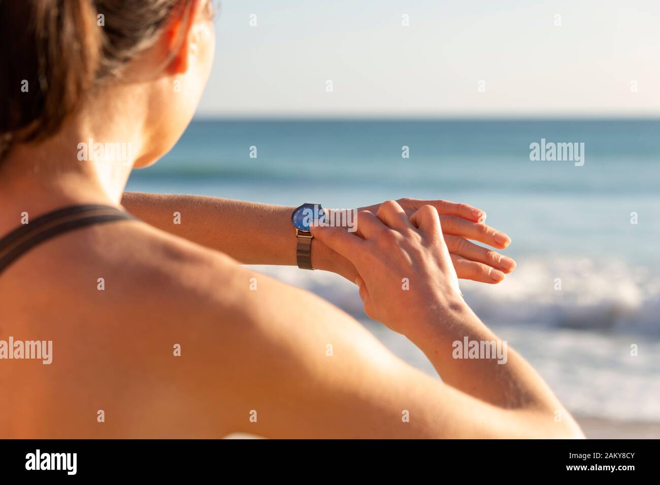 sporty woman checking her watch after running by the sea, close up. Stock Photo