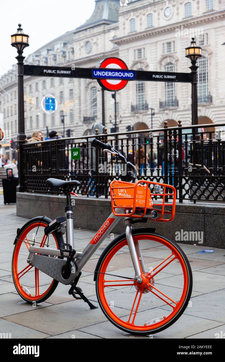 LONDON, UK - December 31, 2019: Bike sharing at London. A rental bike in Piccadilly Circus with the underground exit and London buildings in the backg Stock Photo
