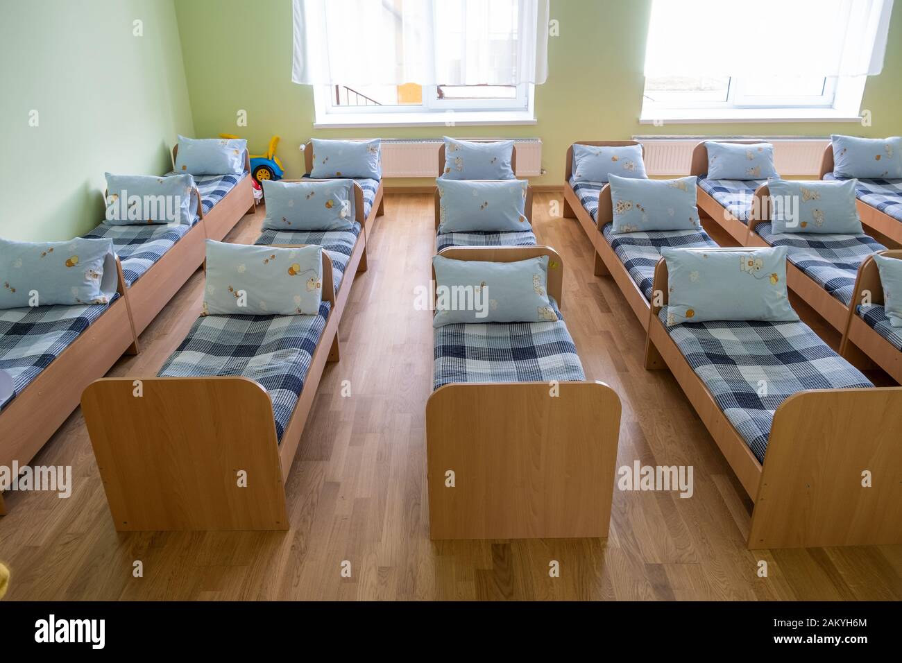 Many small beds with fresh linen in daycare preschool empty bedroom interior for comfortable
