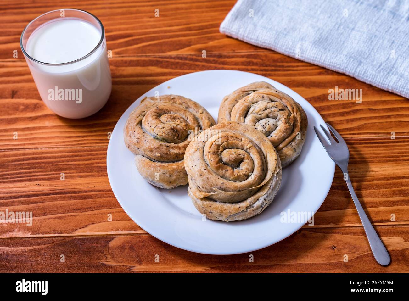 Domestic Home made Rolled pastry with spinach and cheese on a napkin with a glass of Yogurt Stock Photo