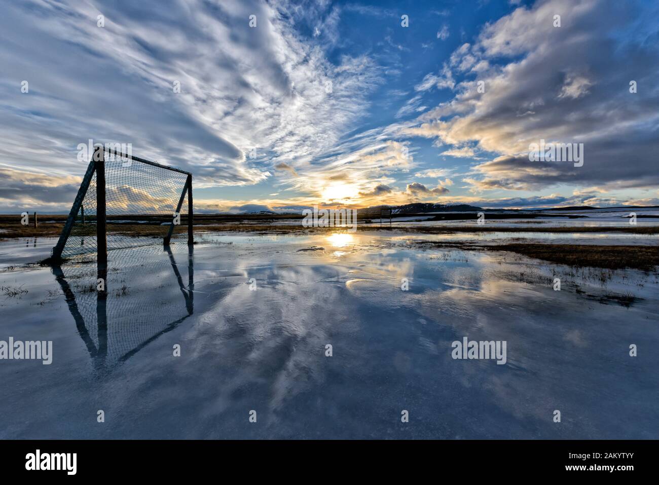 Sunset over clouds, ffootball playground flooded with melting snow, winter at farm Moedrudalur on road from lake Myvatn to Egilsstadir,  Iceland Stock Photo