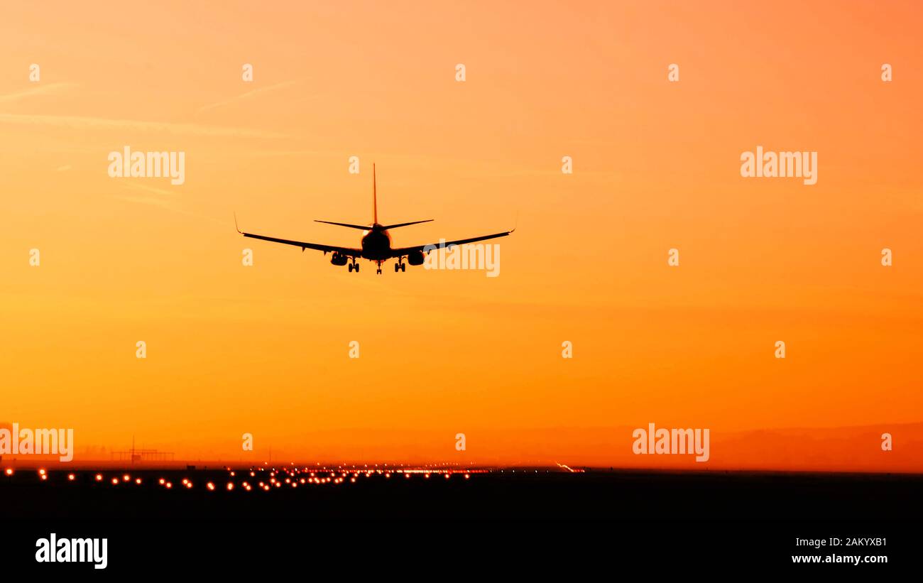 Back View Silhouette Of Airplane Landing At The Airport At Sunny Orange 