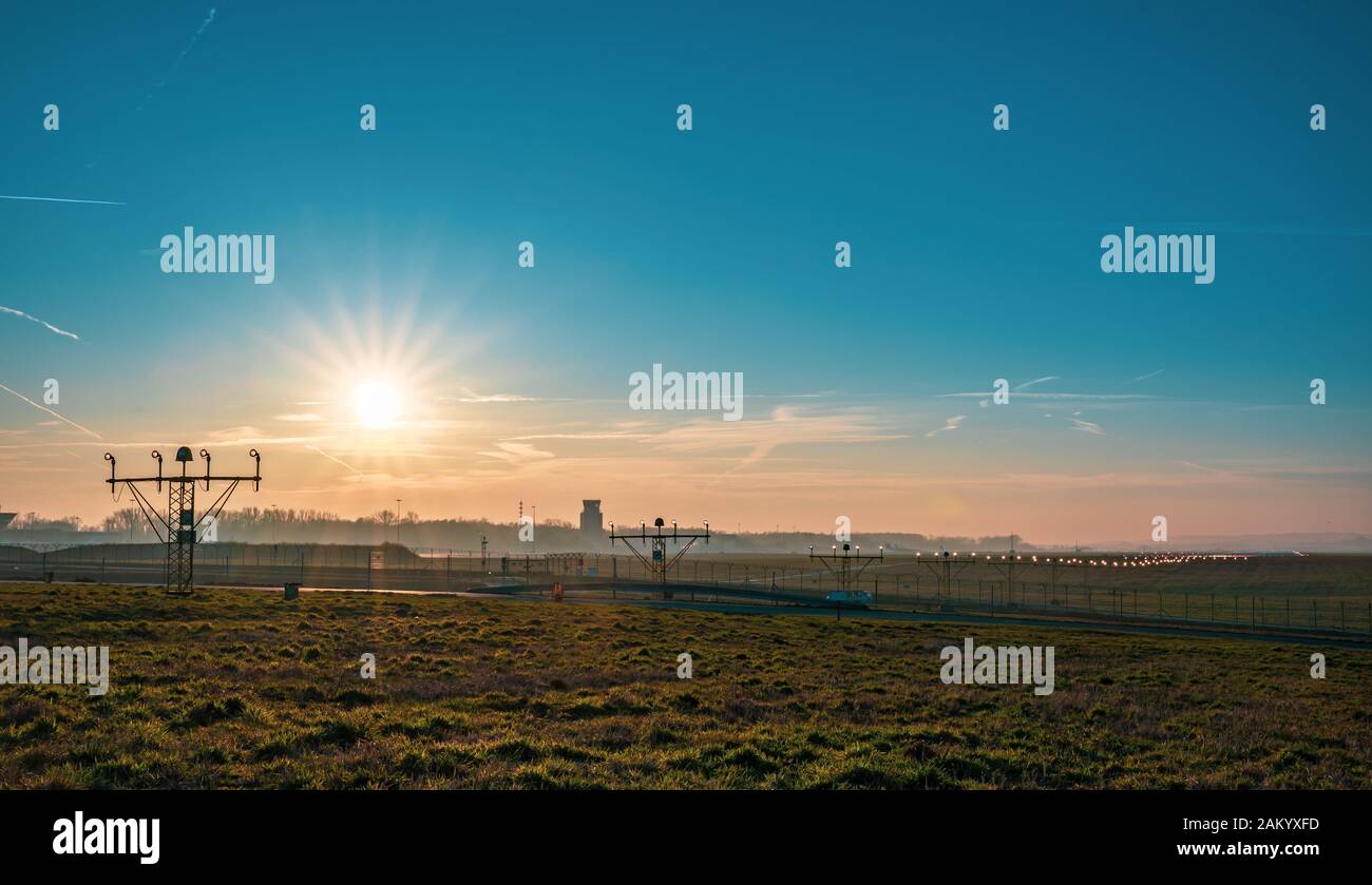 Airport infrastructure at sunny sunset. Runway end identification lights against bright sun and clear sky. Stock Photo