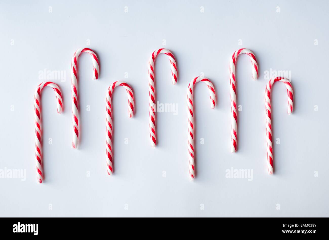 Candy canes arranged in a row on a plain white background. Stock Photo