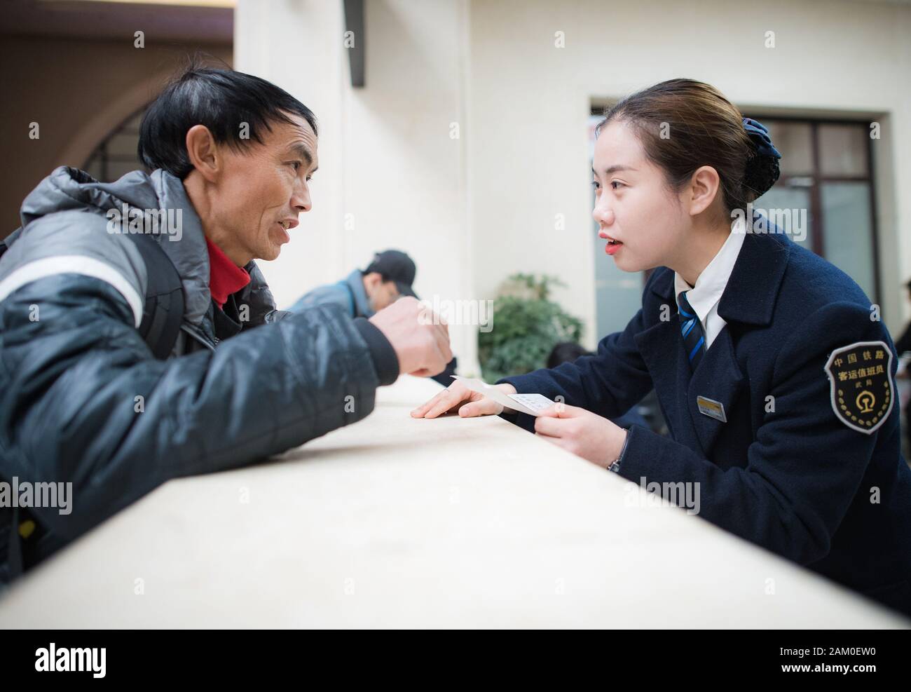 (200111) -- WUHAN, Jan. 11, 2020 (Xinhua) -- Sun Fanjun (R), a ticket inspector, helps a passenger at Hankou Railway Station in Wuhan, central China's Hubei Province, Jan. 5, 2020. China, the world's most populated country, on Jan. 10 ushered in its largest annual migration, 15 days ahead of the Spring Festival, or the Lunar New Year. This year, three billion trips will be made during the travel rush from Jan. 10 to Feb. 18 for family reunions and travel, according to official forecast. The 40-day travel rush is known as Chunyun in Chinese. The Lunar New Year falls on Jan. 25 this year, ear Stock Photo