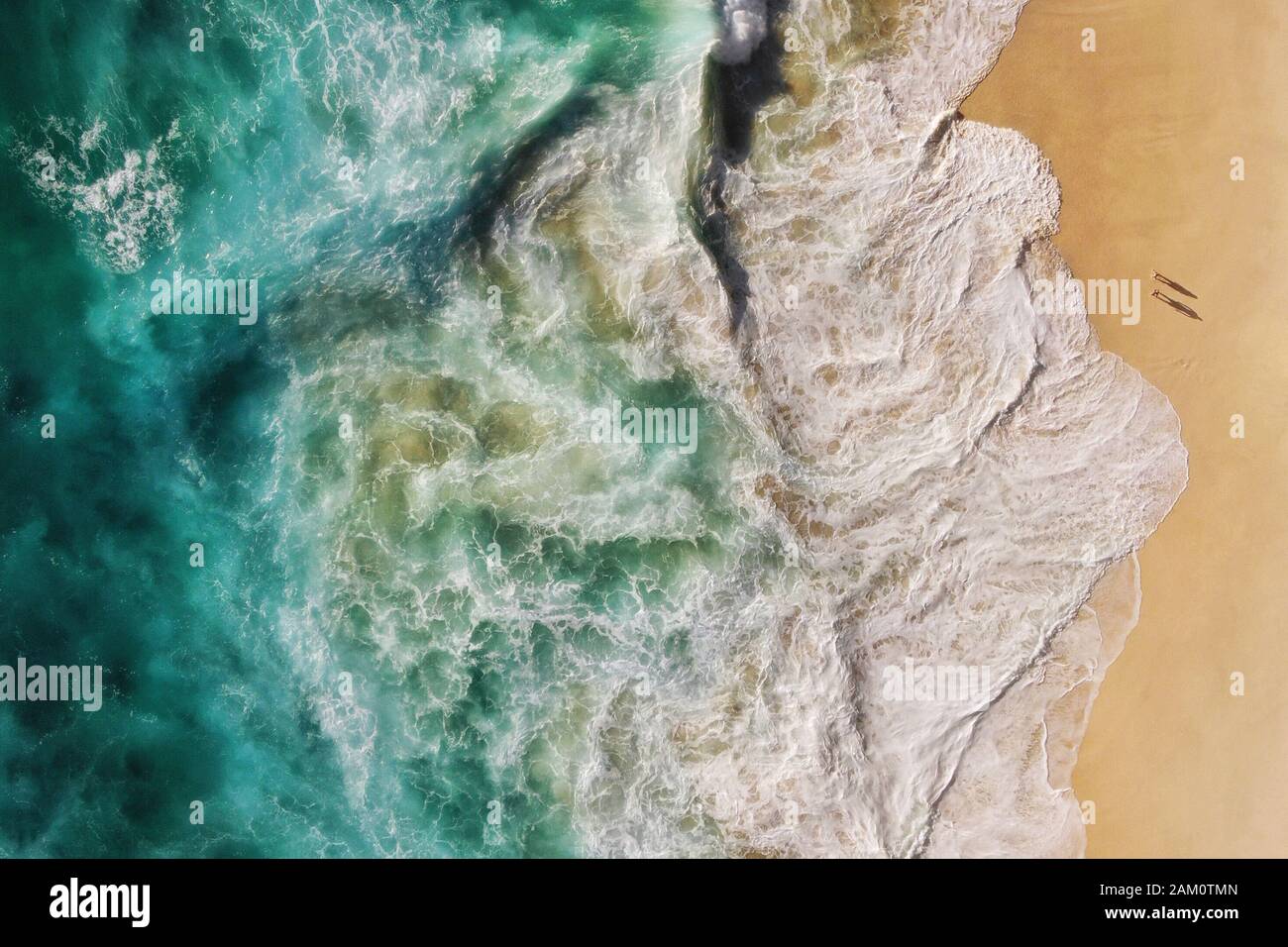 Aerial top down view of turquoise blue ocean waves breaking on the shore of pristine secluded beach in Bali, Indonesia. Stock Photo