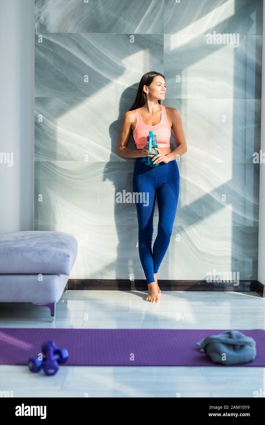 Young woman drinking cold water after fitness at home. Fitness and healthy lifestyle concept with water Stock Photo