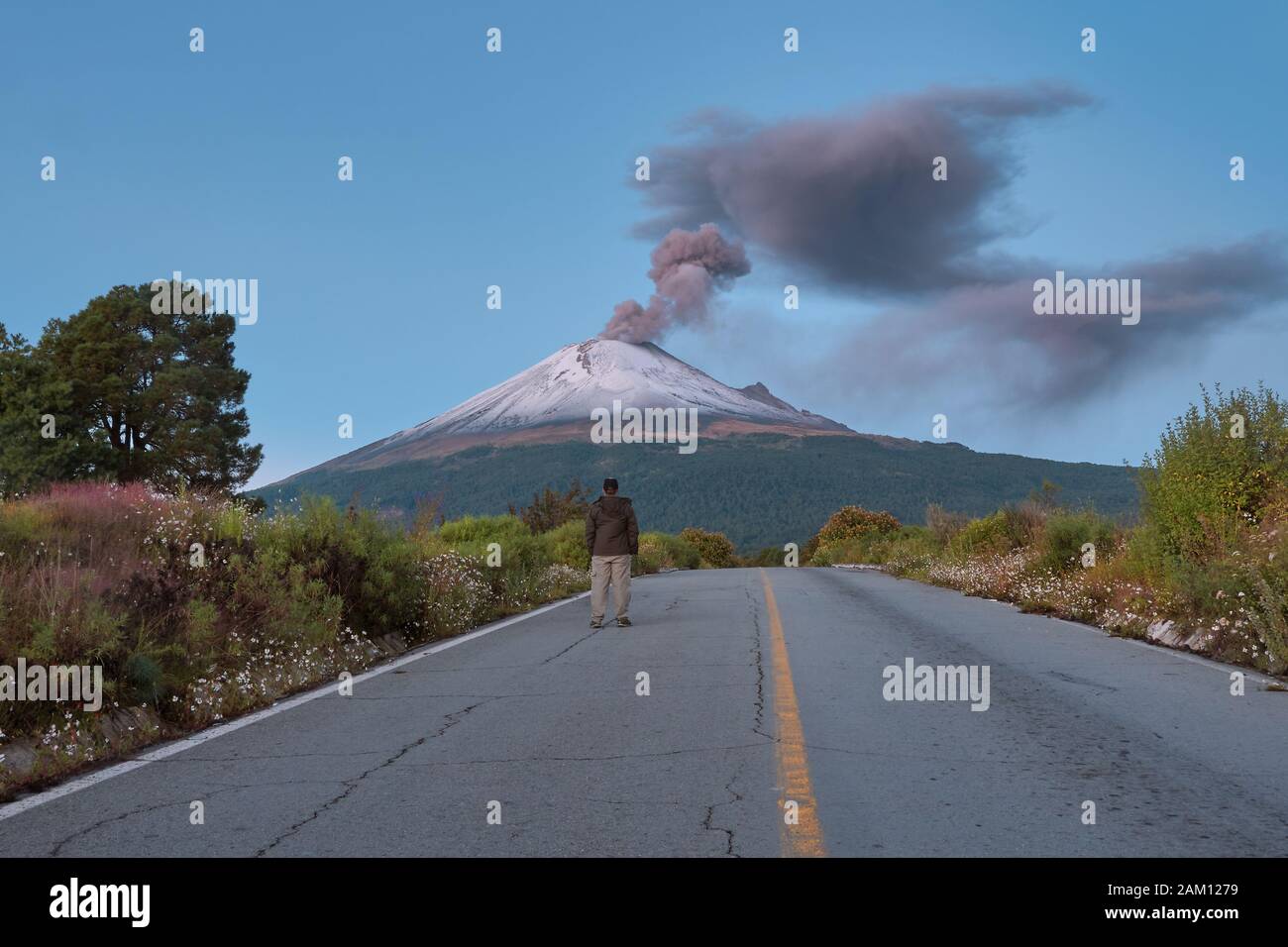 Young man standing on the road to Popocatepetl volcano in Mexico at sunrise Stock Photo