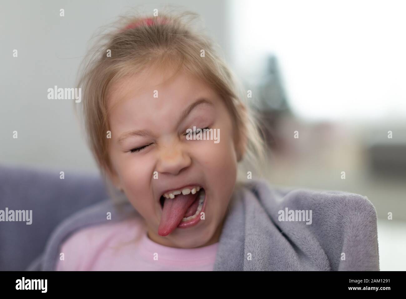 closeup portrait of funny smiling little girl with tongue out and without one front tooth Stock Photo