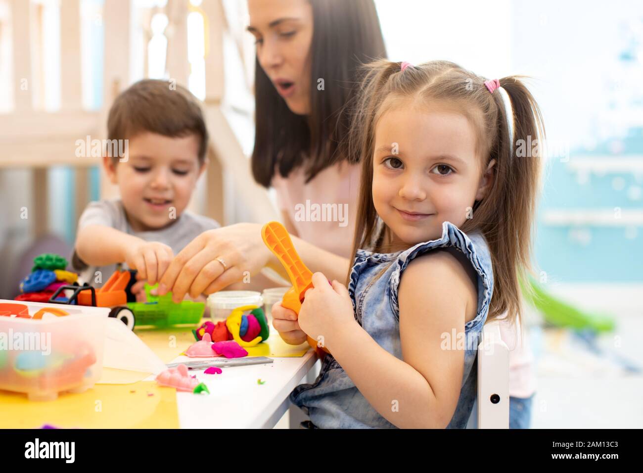 Female teacher teaches children handcraft in kindergarten or playschool Stock Photo