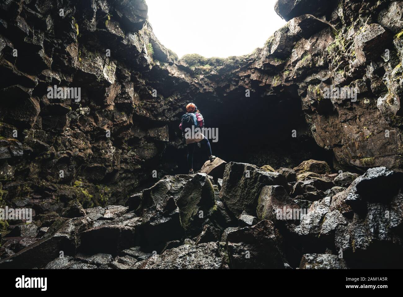 Woman traveler explore lava tunnel in Iceland. Raufarholshellir is a beautiful hidden world of cave. It is one of the longest and best-known lava tube Stock Photo